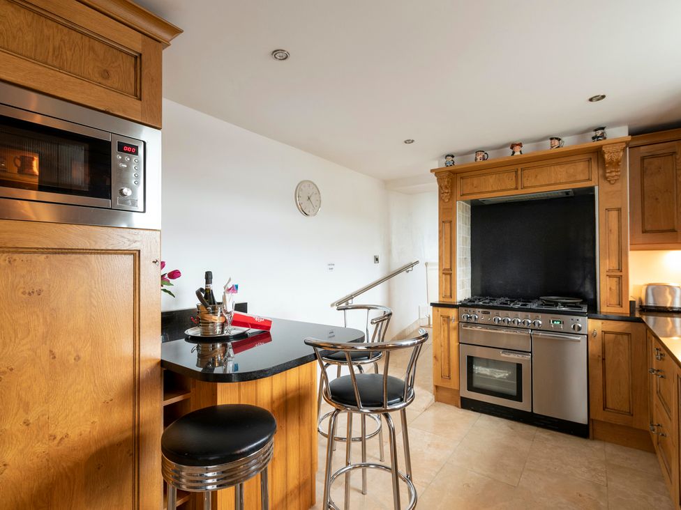 A kitchen with a stove and bar stools at Bank House Cottage in Lancaster