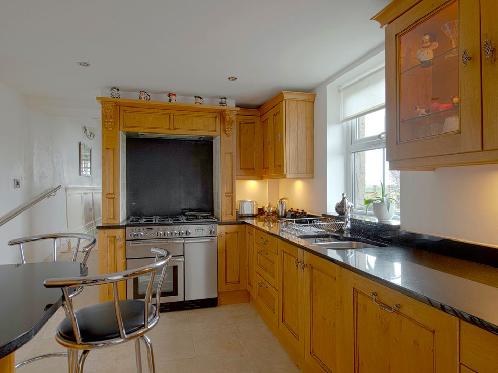 A kitchen with wooden cabinets and a stove at Bank House Cottage in Lancaster