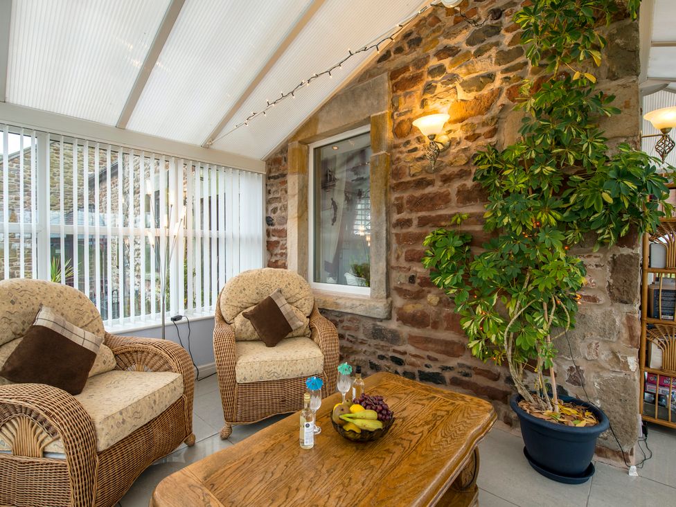 A conservatory with chairs and a table at Bank House Cottage in Lancaster