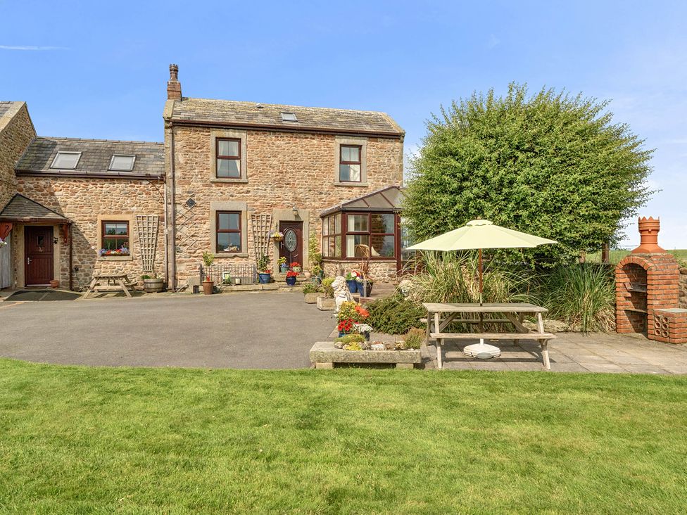 An outdoor area with a house, table, umbrella and garden at Bank House Cottage in Glasson Dock