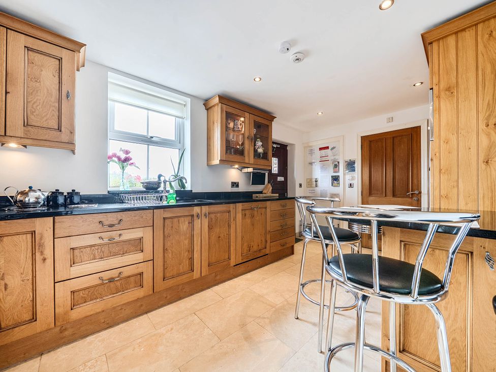 A kitchen with wooden cabinets and a sink at Bank House Cottage in Glasson Dock
