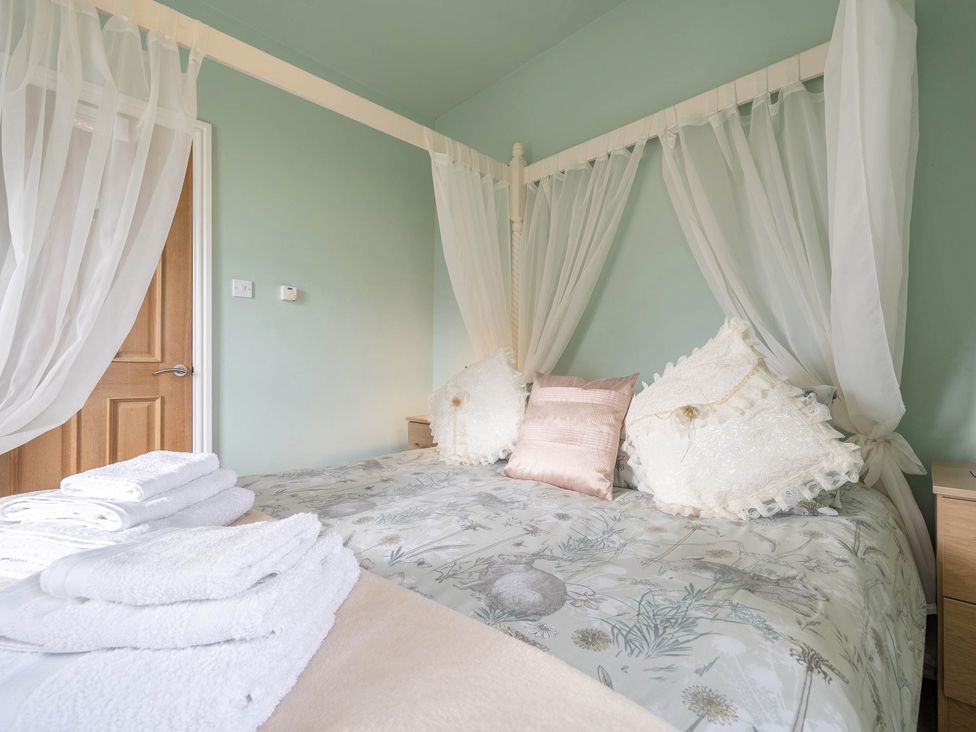 A bedroom with a bed and towels at Bank House Cottage in Glasson Dock