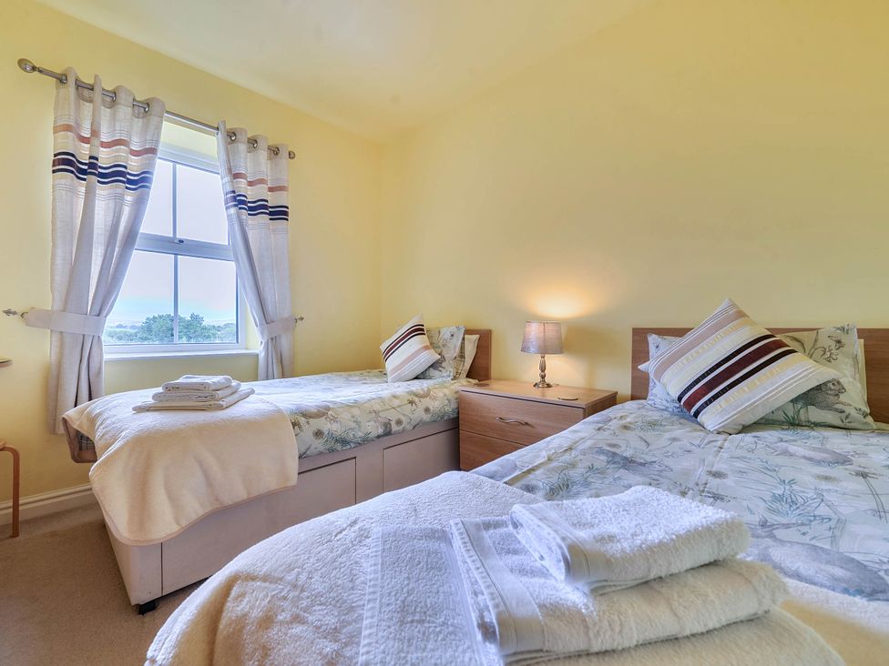 A bedroom with two single beds and a bedside table at Bank House Cottage in Glasson Dock