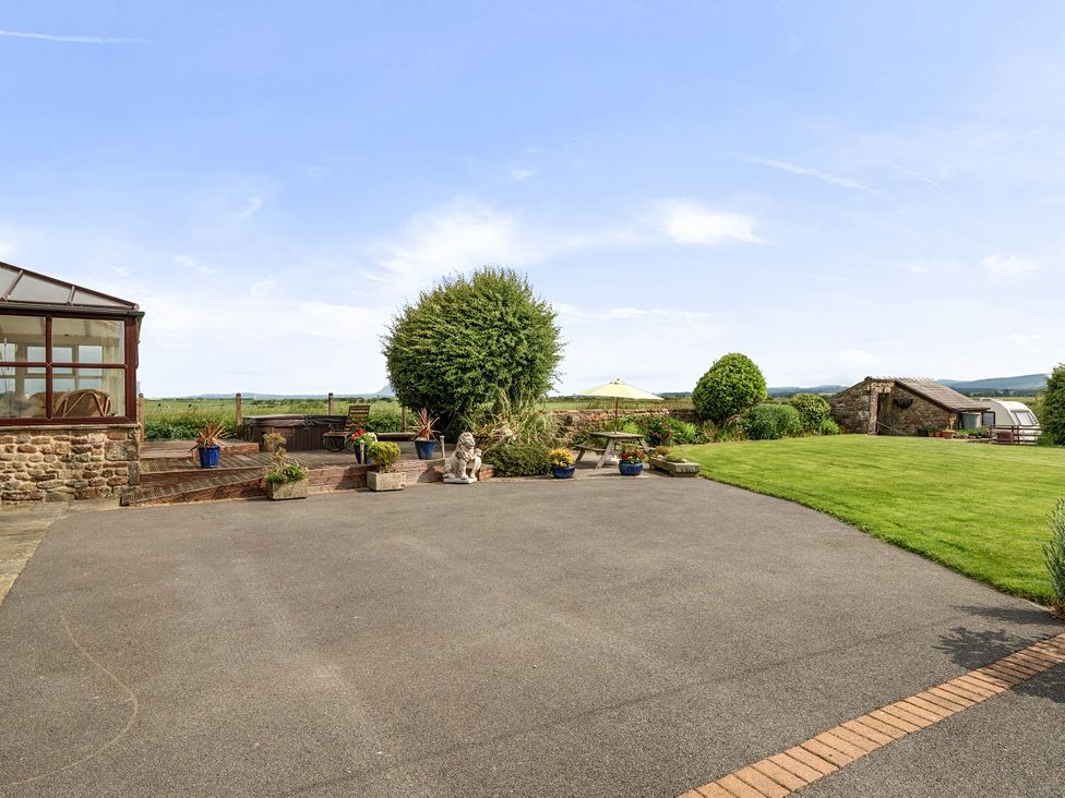 A garden with a conservatory and seating area at Bank House Cottage Glasson Dock