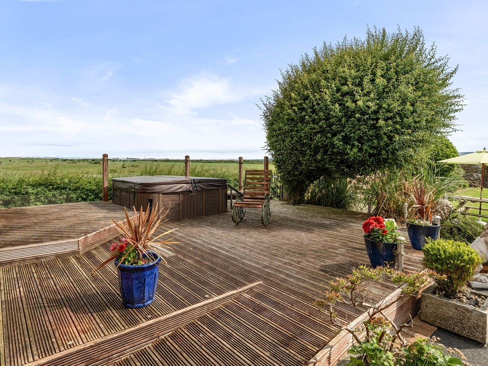 A deck with a hot tub and flower pots at Bank House Cottage, Glasson Dock