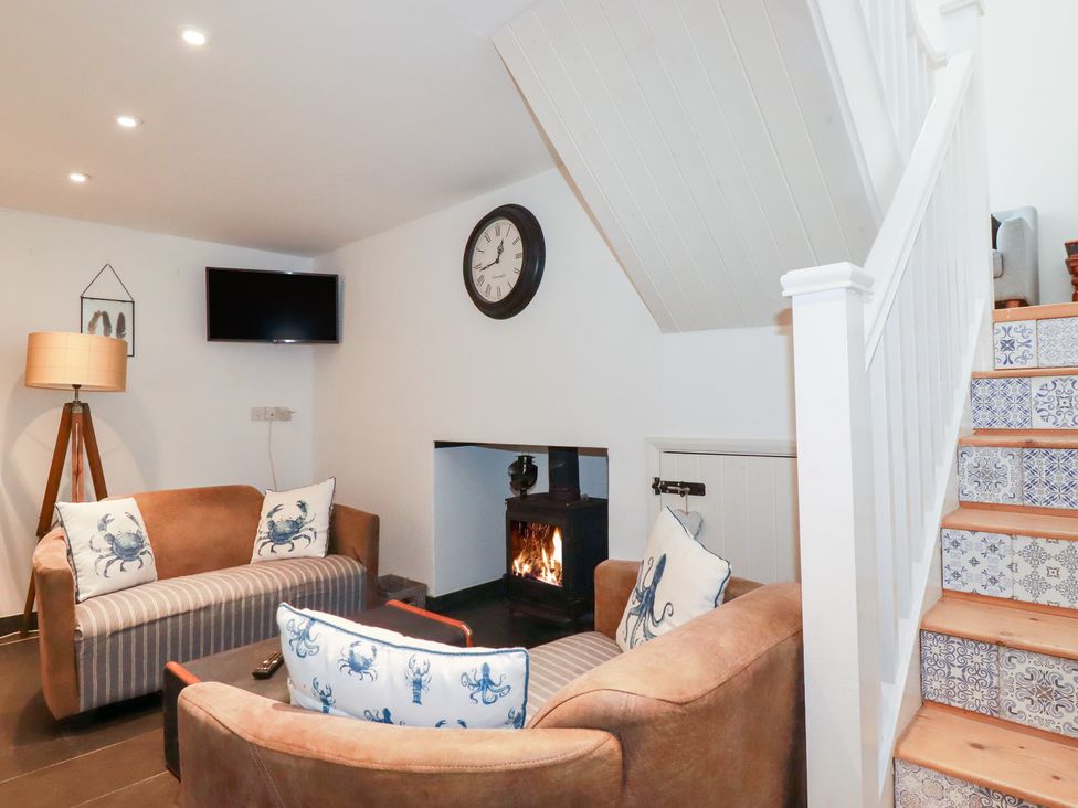 A living room with a sofa and television at Mill Pond Cottage in Bude