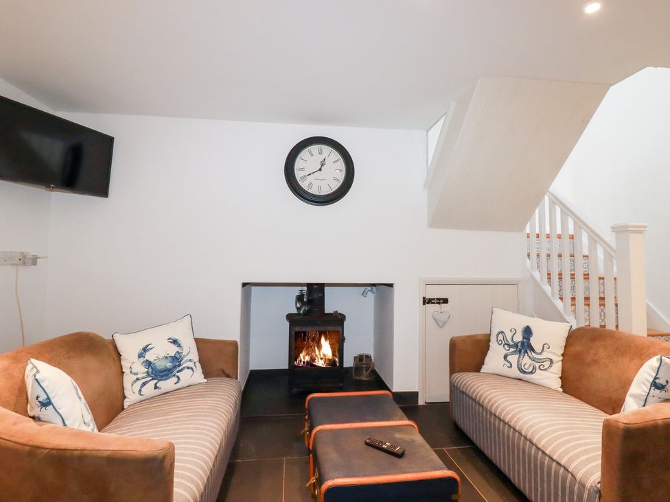 A living room with sofas and a fireplace at Mill Pond Cottage in Bude