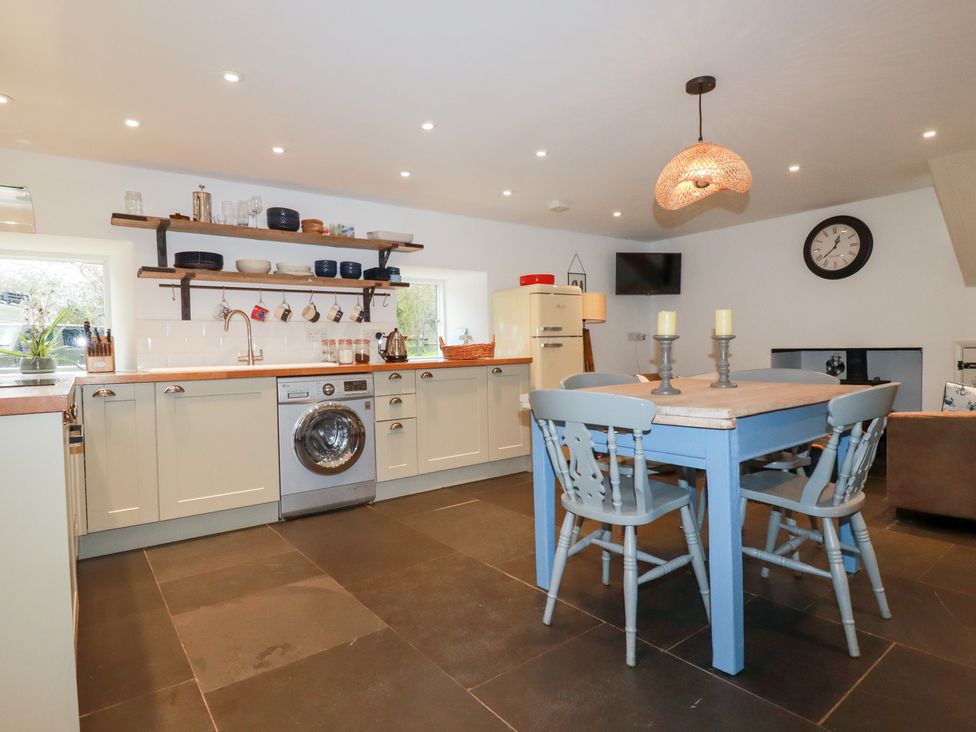 A kitchen with appliances and dining table at Mill Pond Cottage in Bude