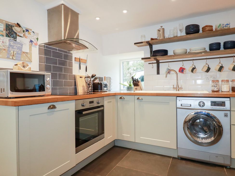 A kitchen with a microwave, oven, and washing machine at Mill Pond Cottage in Bude