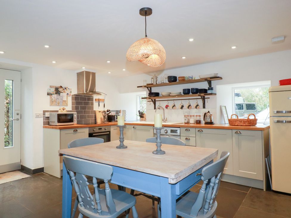 A kitchen with a dining table and appliances at Mill Pond Cottage in Bude