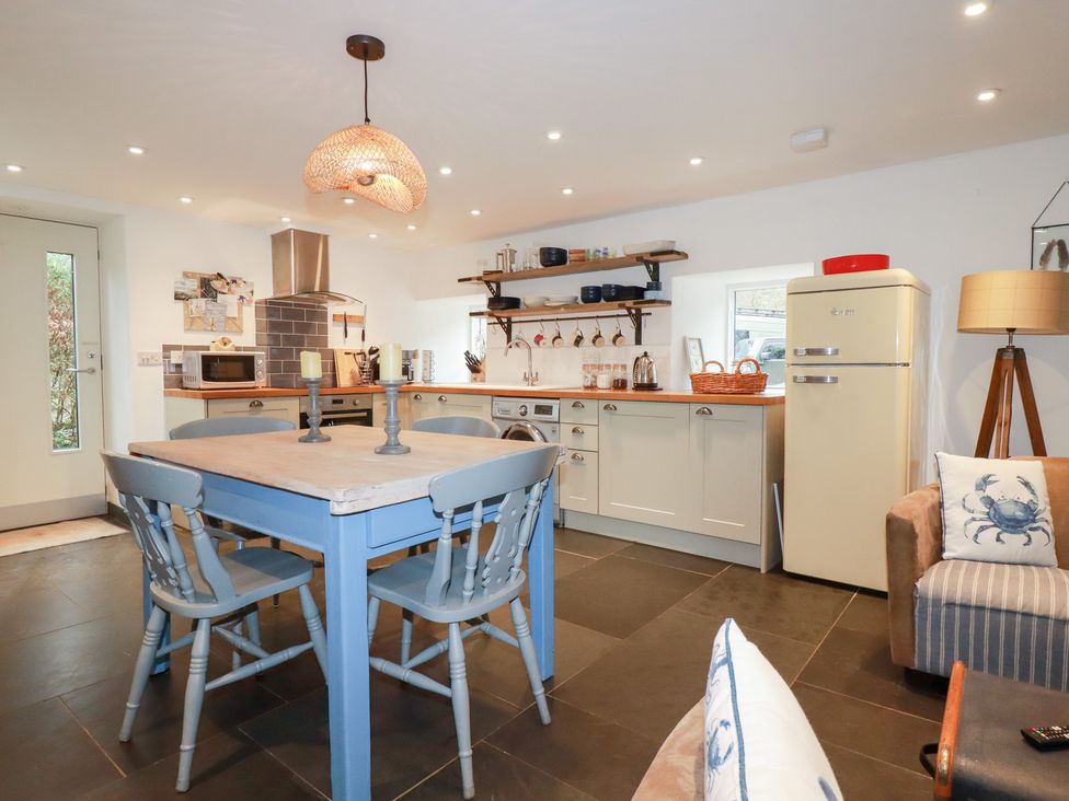 A kitchen with a wooden table and chairs at Mill Pond Cottage in Bude
