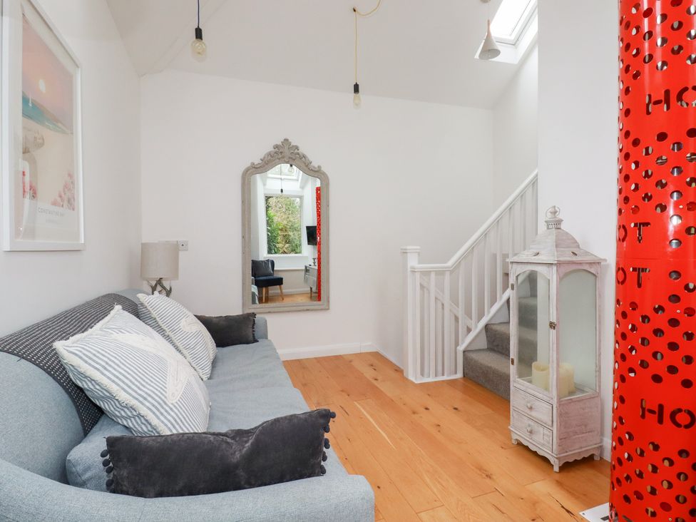 A living room with a sofa and a mirror at Mill Pond Cottage in Bude