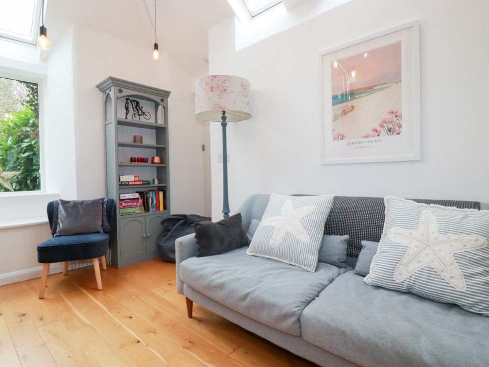 A living room with a sofa and bookshelf at Mill Pond Cottage in Bude