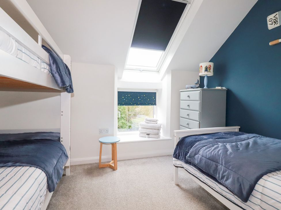 A bedroom with a bunk bed and single bed at Mill Pond Cottage in Bude