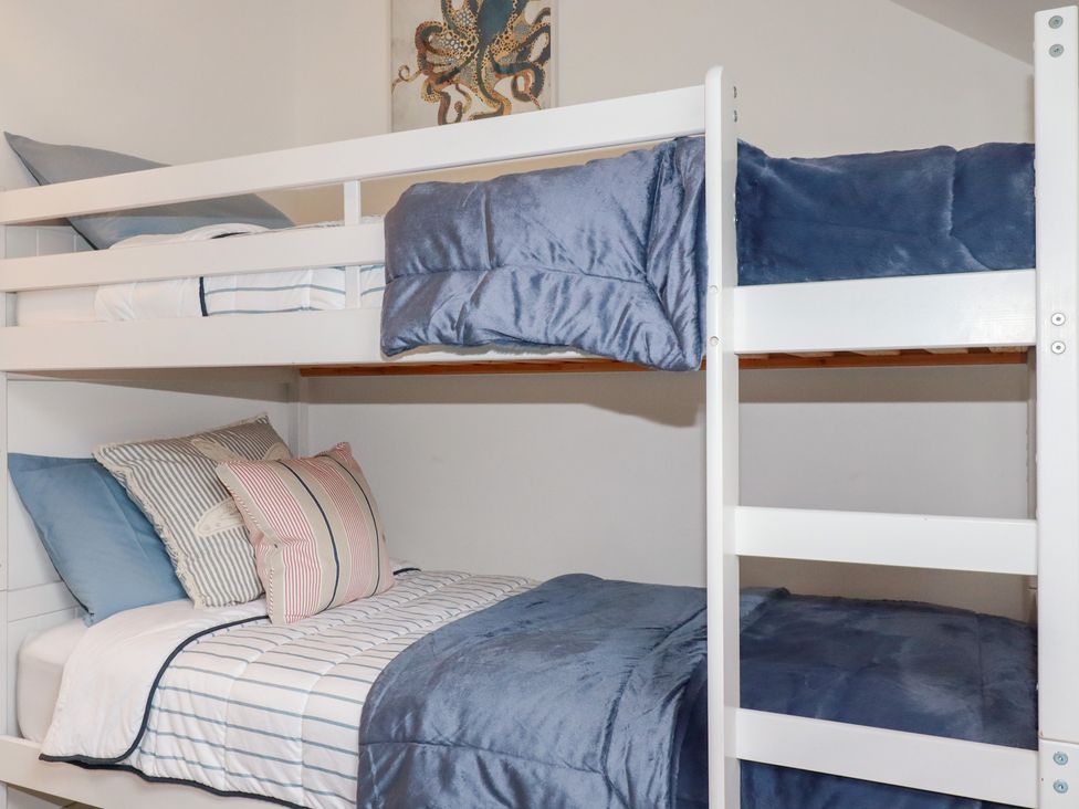 A bunk bed with striped bedding and pillows at Mill Pond Cottage in Bude