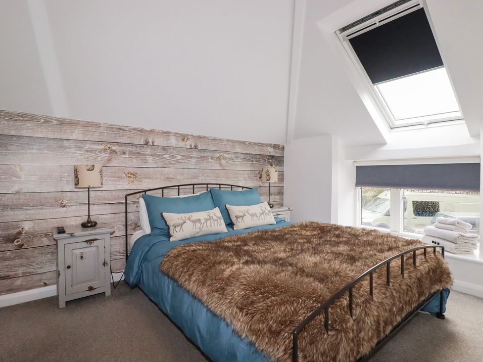 A bedroom with a bed and a window at Mill Pond Cottage in Bude