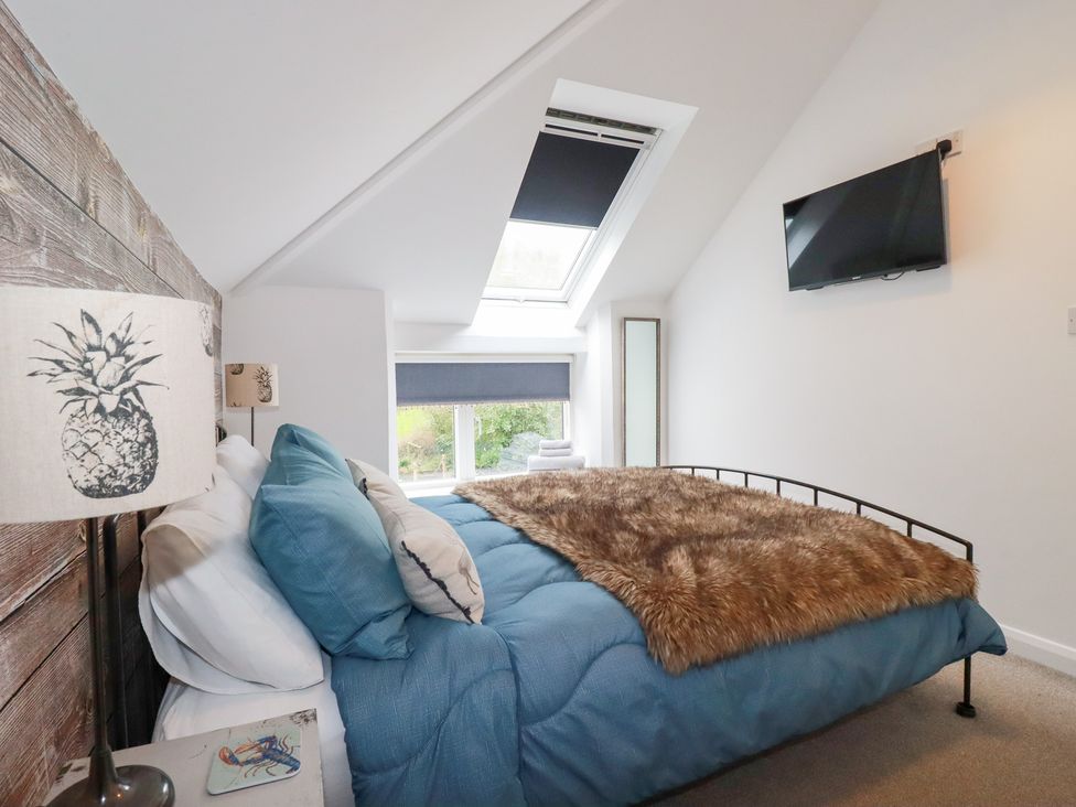A bedroom with a bed and television at Mill Pond Cottage Bude