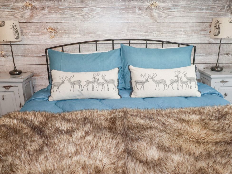 A bedroom with a bed and decorative pillows at Mill Pond Cottage in Bude