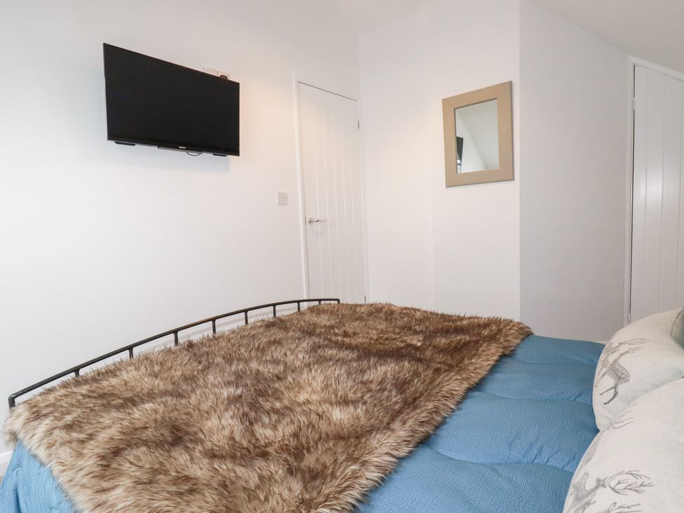 A bedroom with a bed and television at Mill Pond Cottage in Bude