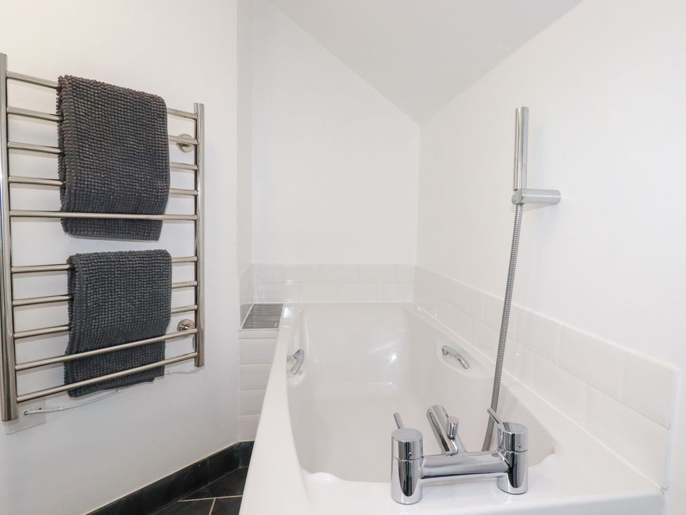 A bathroom with a bathtub and towel rack at Mill Pond Cottage in Bude