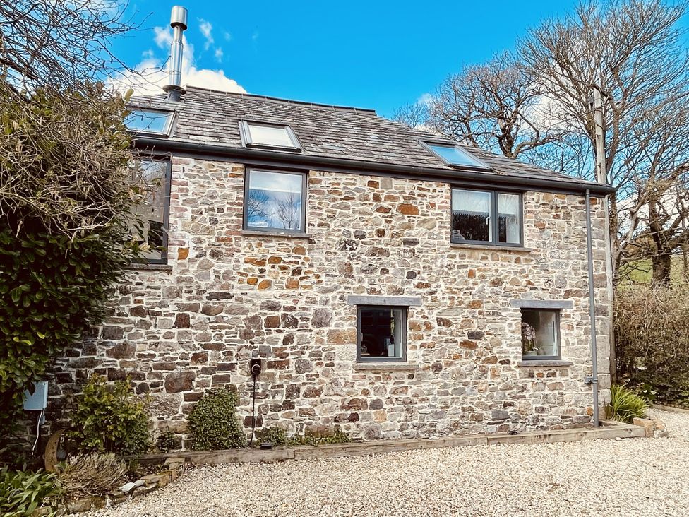 An outdoor view of a stone house with windows at Mill Pond Cottage in Widemouth Bay