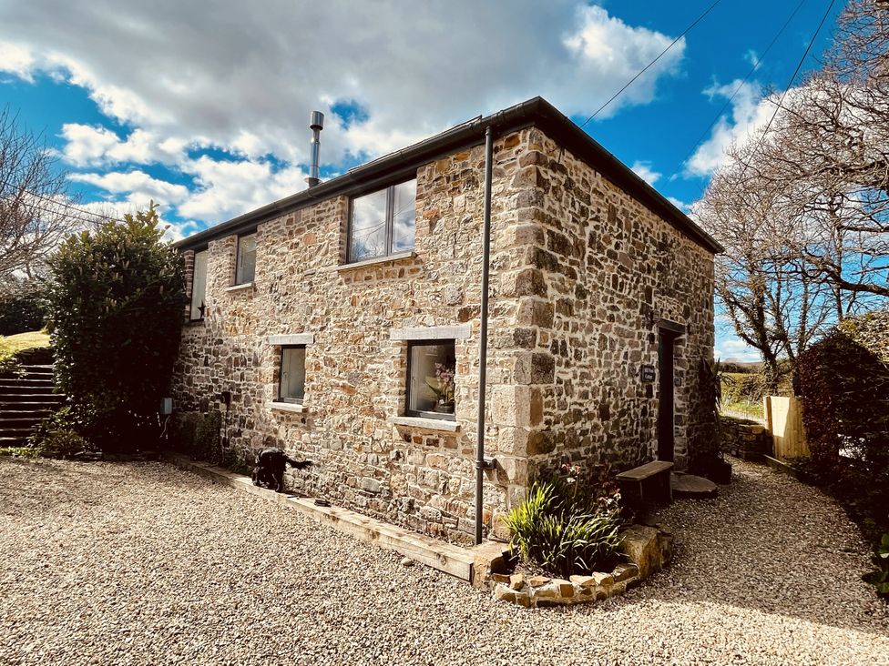 A stone house with windows and steps at Mill Pond Cottage in Widemouth Bay