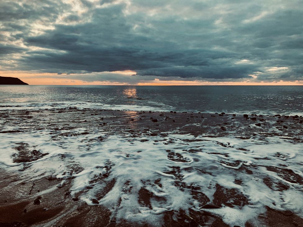 A beach view with waves and clouds at Mill Pond Cottage in Widemouth Bay