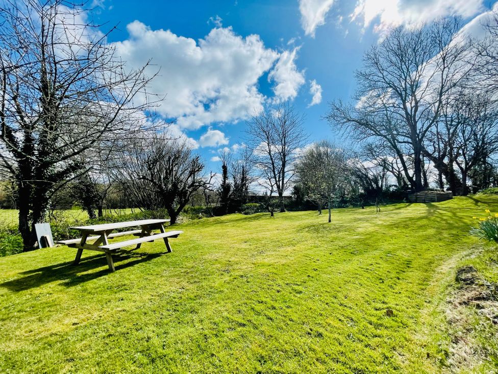A garden with a picnic bench and trees at Mill Pond Cottage in Widemouth Bay