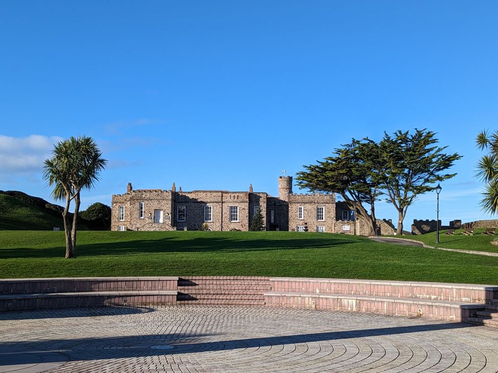 A building with palm trees and a pathway at Mill Pond Cottage in Widemouth Bay