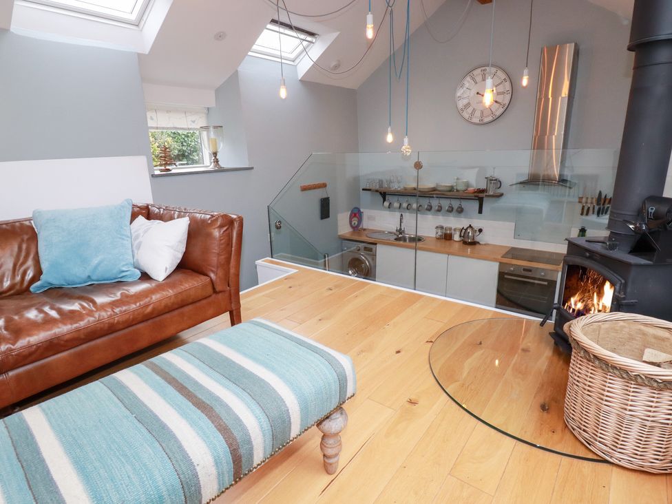 A living room with a sofa and kitchenette at Meadow View in Bude