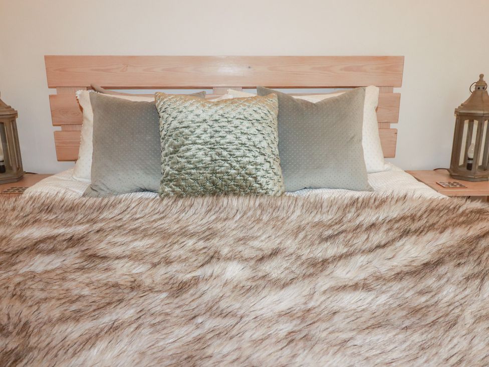 A bed with pillows and a blanket at Meadow View in Bude