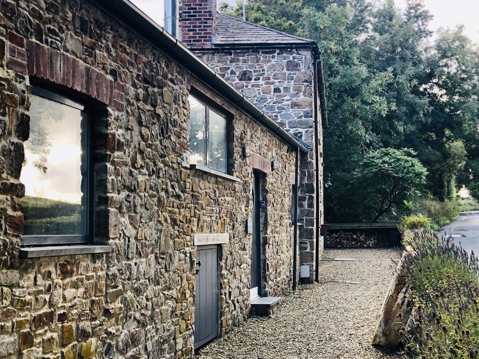 An outdoor view of a stone building with windows and a door at Meadow View in Widemouth Bay