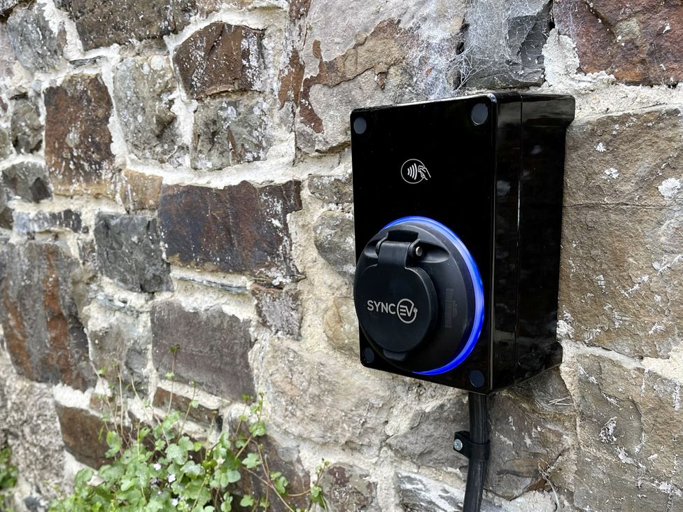 An electric vehicle charging station on a stone wall at Meadow View in Widemouth Bay