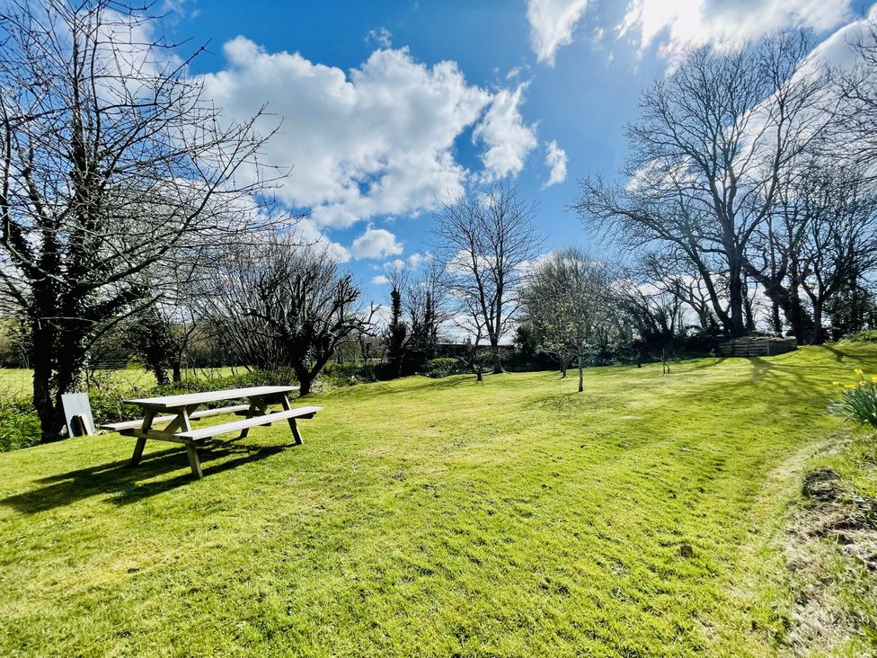 A garden with a picnic table and trees at Meadow View in Widemouth Bay