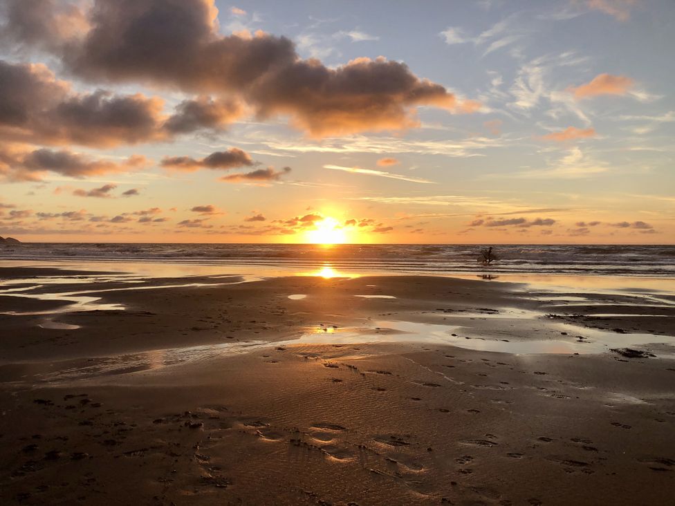 A sunset over the ocean with sand at Meadow View in Widemouth Bay