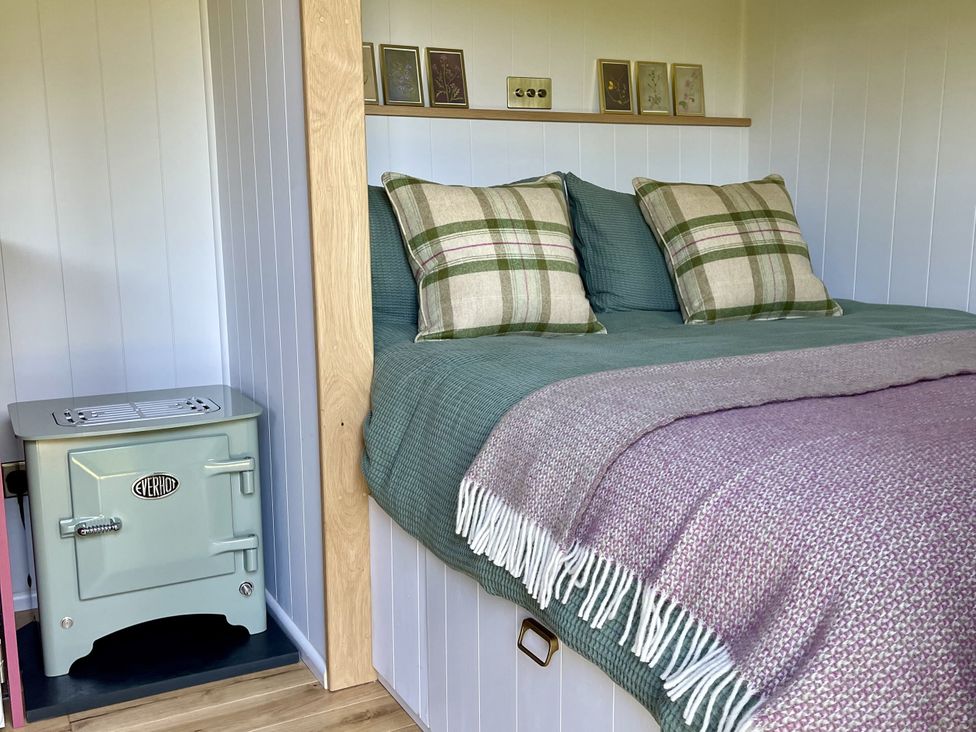 A bedroom with a bed and stove at Bryar Widemouth Bay