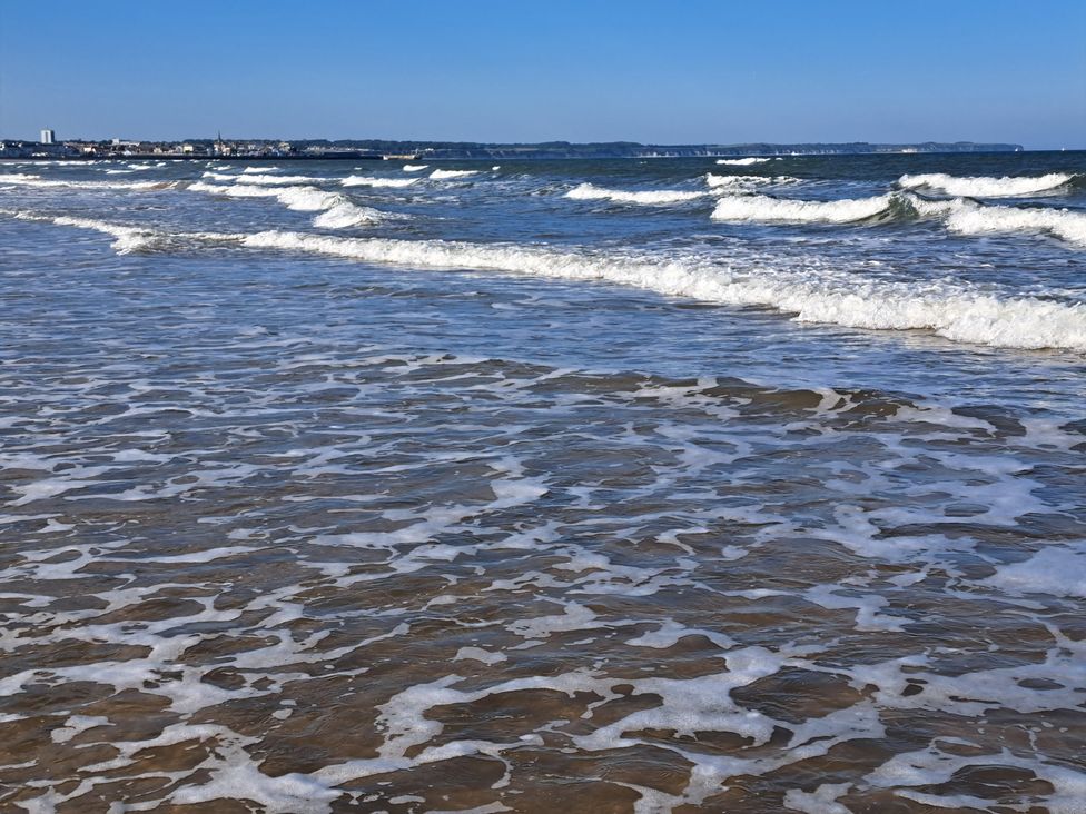 A beach with waves and sand at Sea View Retreat in Bridlington