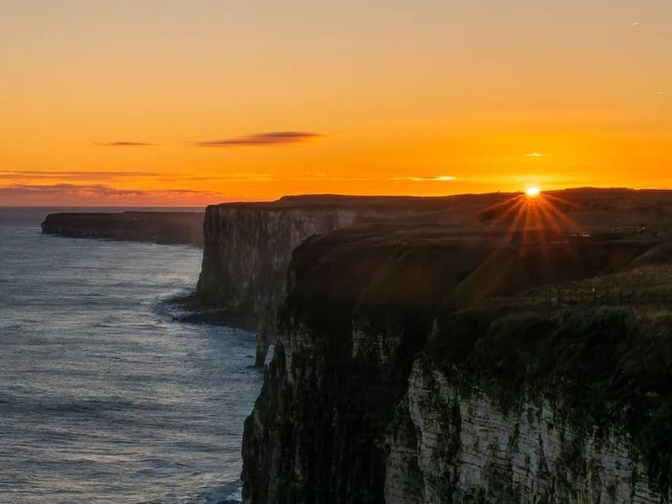 A sunset over cliffs and ocean at Sea View Retreat in Bridlington