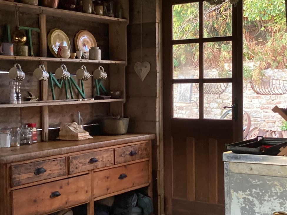 A kitchen with a wooden cabinet and mugs on a shelf at The Tree House in the Woods Longhope