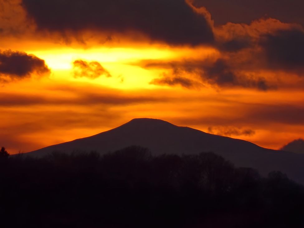 A mountain silhouetted against a sunset sky at The Tree House in the Woods Longhope