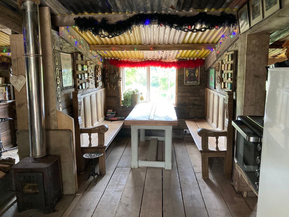 A dining room with a wooden table and benches at Cosy Shepherd’s Hut in Longhope