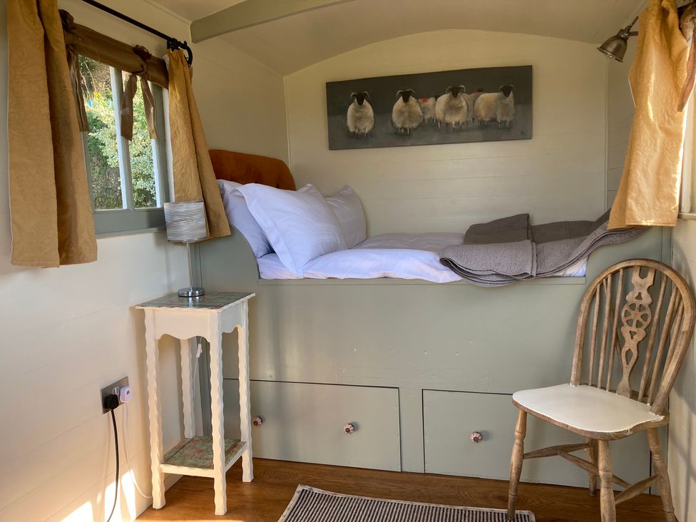 A bedroom with a bed and chair at Cosy Shepherd’s Hut Longhope