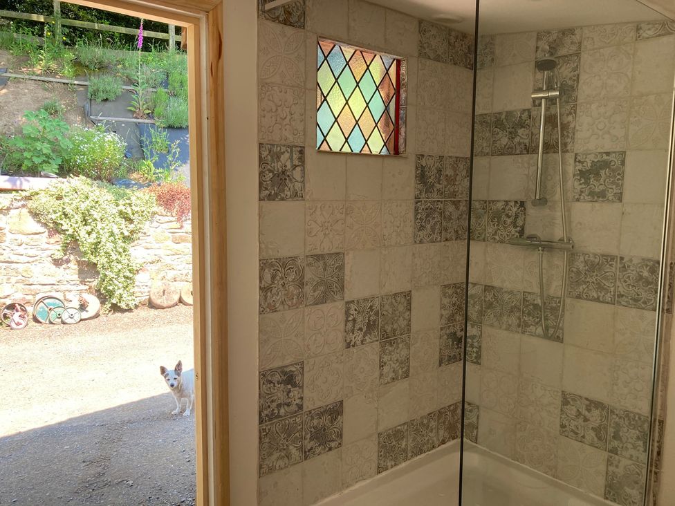 A bathroom with a shower and window at Cosy Shepherd’s Hut Longhope