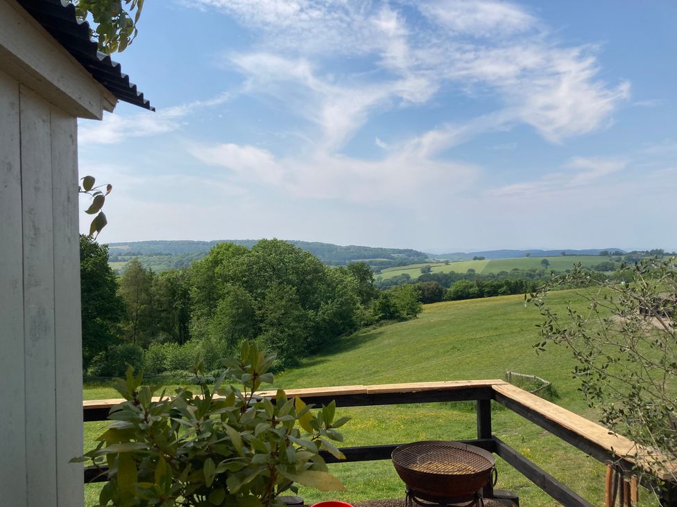 A view of a green field and hills from a balcony at Cosy Shepherd’s Hut Longhope