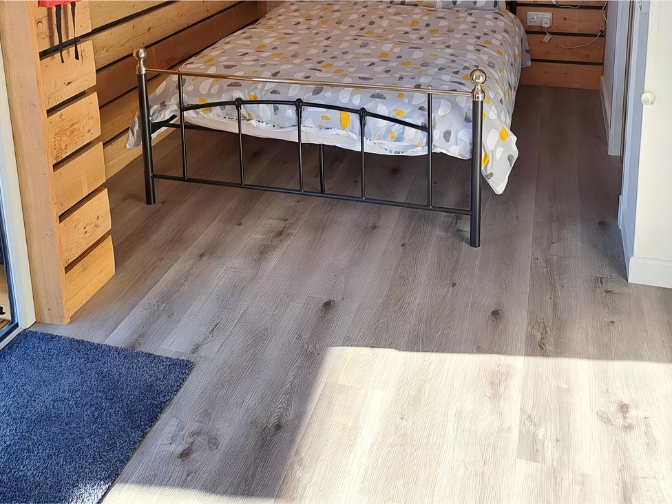 A bedroom with a bed and wooden walls at The Posh Bothy in Roy Bridge
