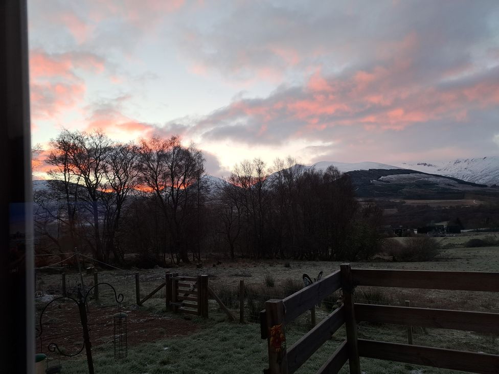 A view of trees and mountains at sunset at The Posh Bothy Roy Bridge