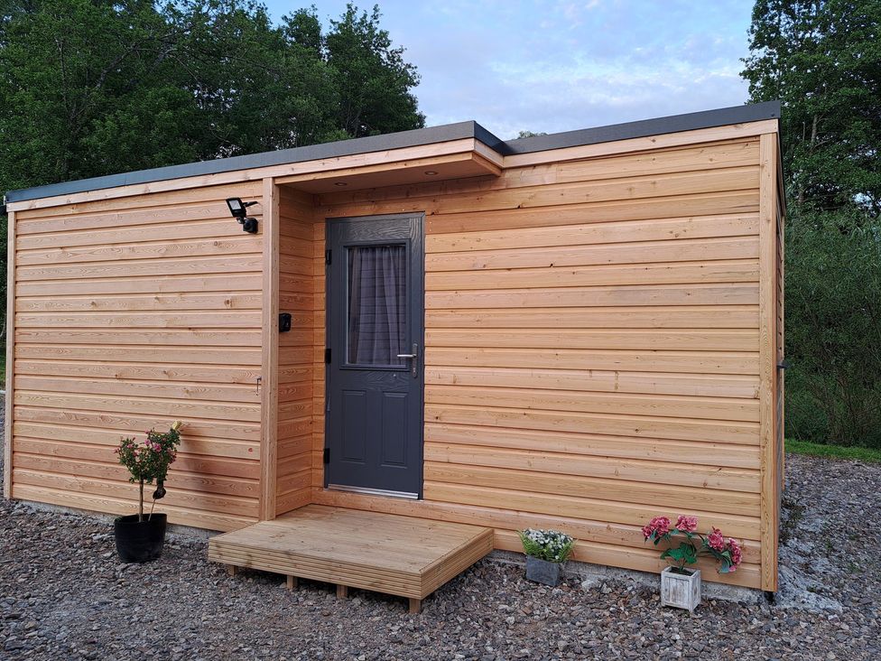 An outdoor view of a wooden building with a door and window at The Posh Bothy 2 in Roy Bridge