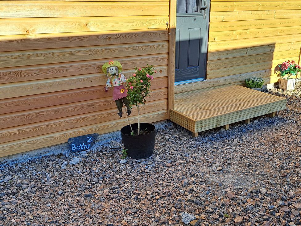 An outdoor area with a flower pot and a scarecrow near the door at The Posh Bothy 2 Roy Bridge