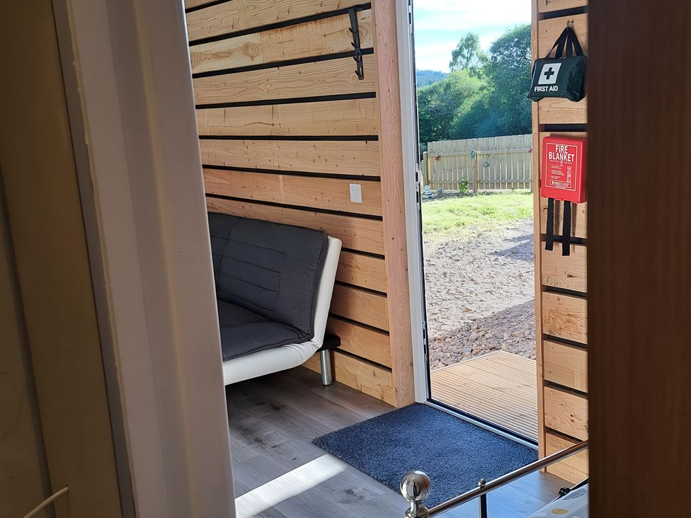 A room with a sofa and door to the outdoor area at The Posh Bothy 2 in Roy Bridge