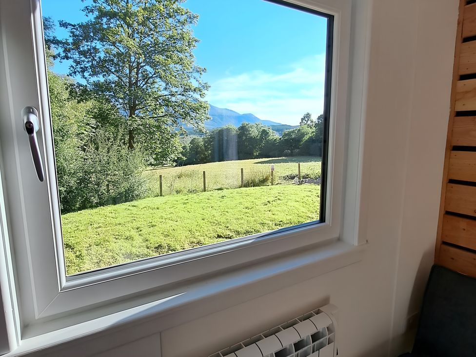 A window view of trees and a field at The Posh Bothy 2 in Roy Bridge